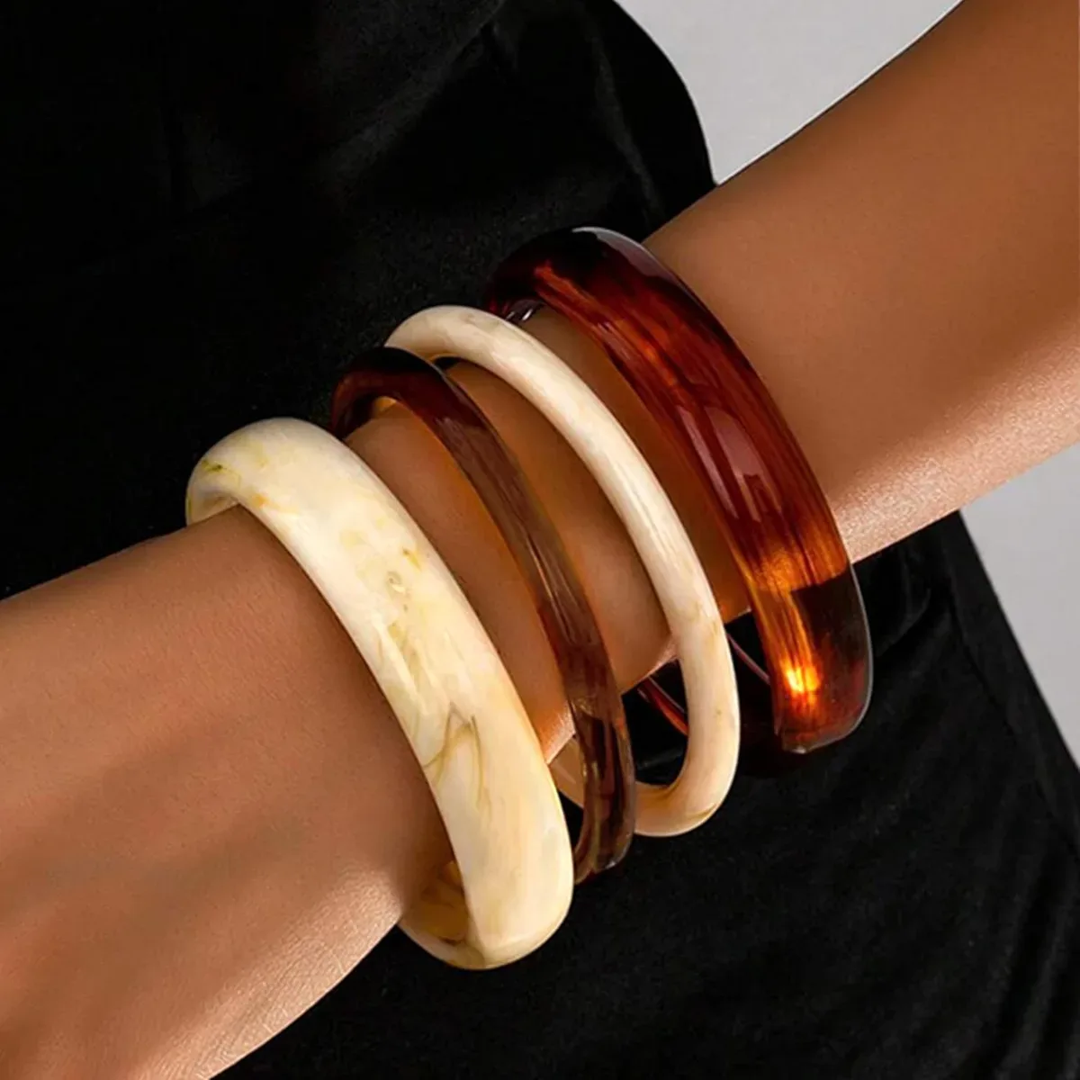 Chunky resin bangles worn as a full four-piece stack on the wrist