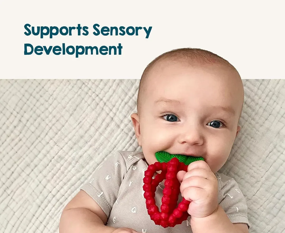 Baby chewing on a strawberry teether to soothe gums