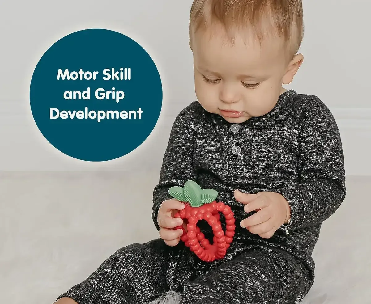 Baby gripping a silicone strawberry teether with both hands